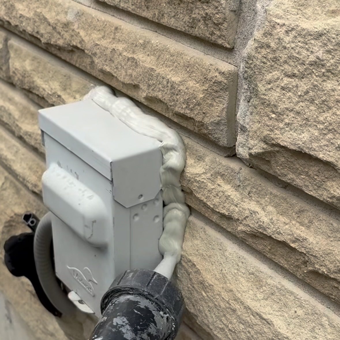 Applying silicone around an exterior box on a stone facade in Mississauga