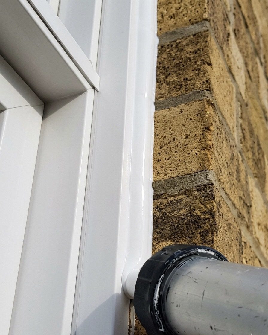 Applying fresh silicone evenly between the window frame and brick facade